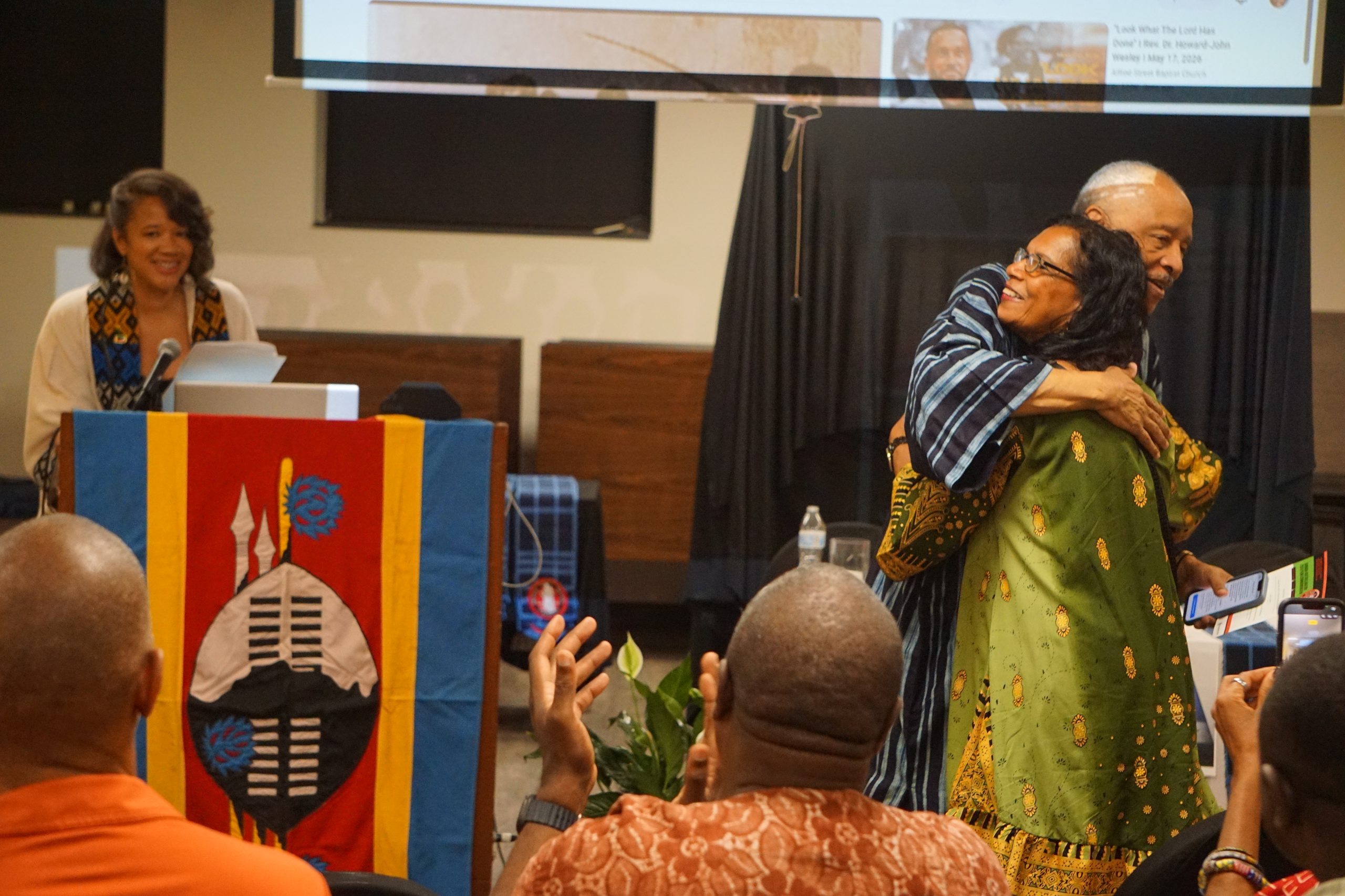 Attendees embracing at an indoor reparations event